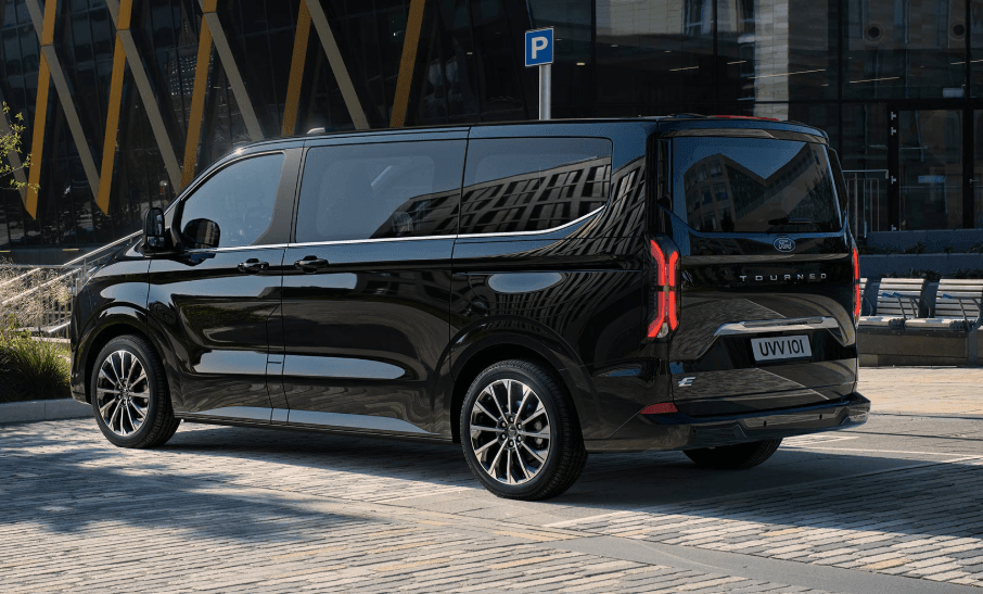 Black van parked on a city street with modern glass buildings in the background.