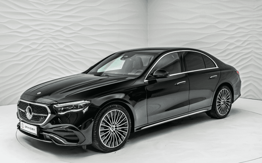 Sleek black luxury sedan with modern design, parked in an indoor showroom with textured walls.